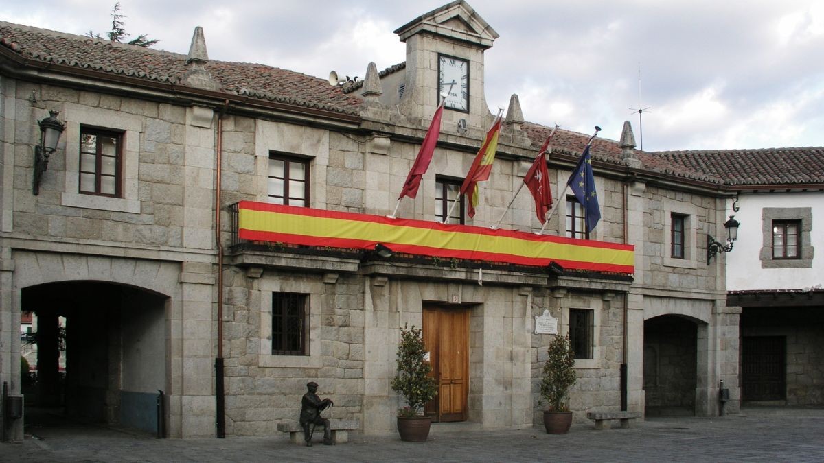 Casa gratis con los recibos pagados: oferta de empleo en una finca en Guadarrama. Ayuntamiento de Guadarrama adornado con una bandera española.