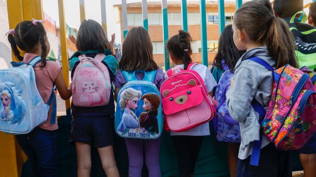 niñas de espaldas mirando hacia el interior del patio de un colegio público