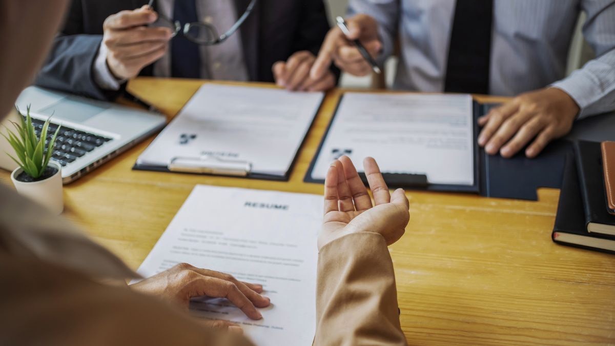 Contratación interna o externalizar el servicio: ¿qué es mejor? Persona revisando un currículum junto a otras dos personas