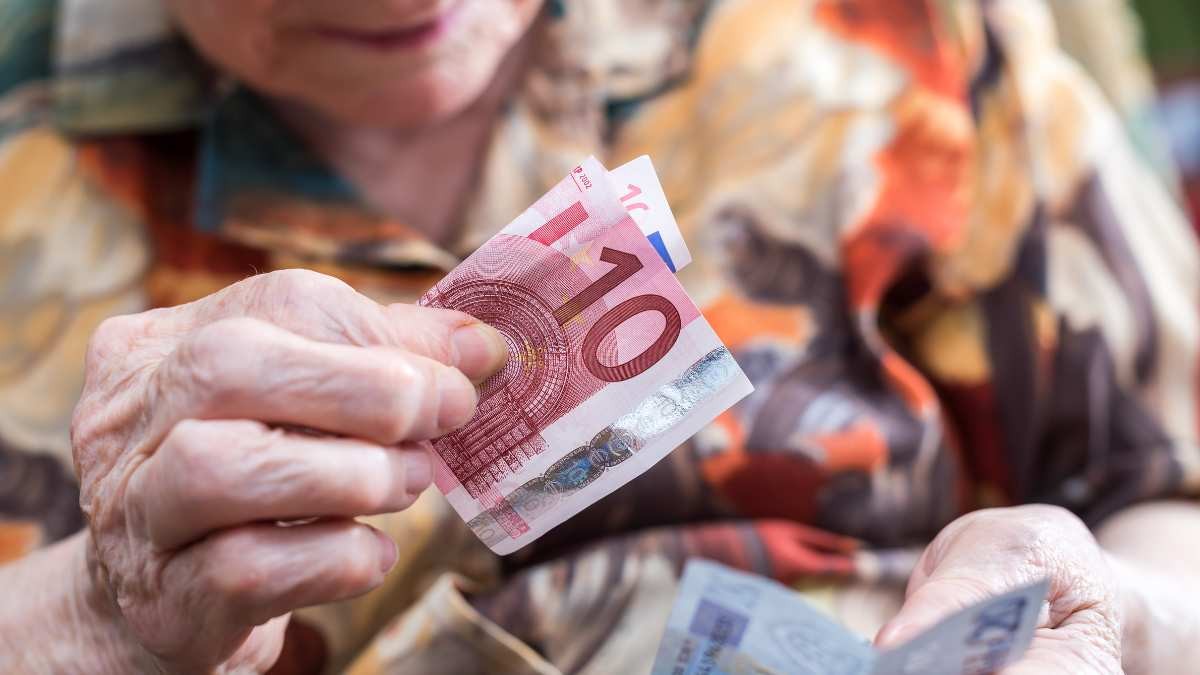 Una pensionista encuentra en casa miles de euros perdidos para pagar sus deudas: el banco se niega a aceptar ese dinero Las manos de una anciana sujetando billetes de euro