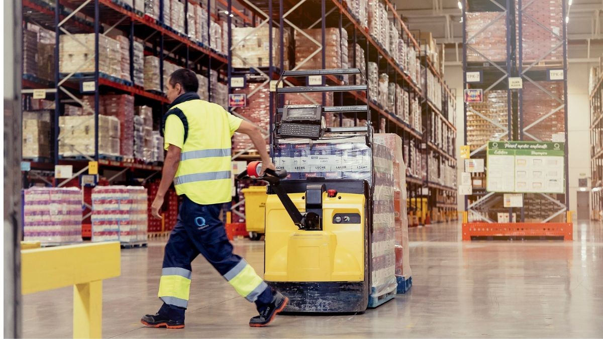 Un trabajador de almacén arrastra una carretilla.