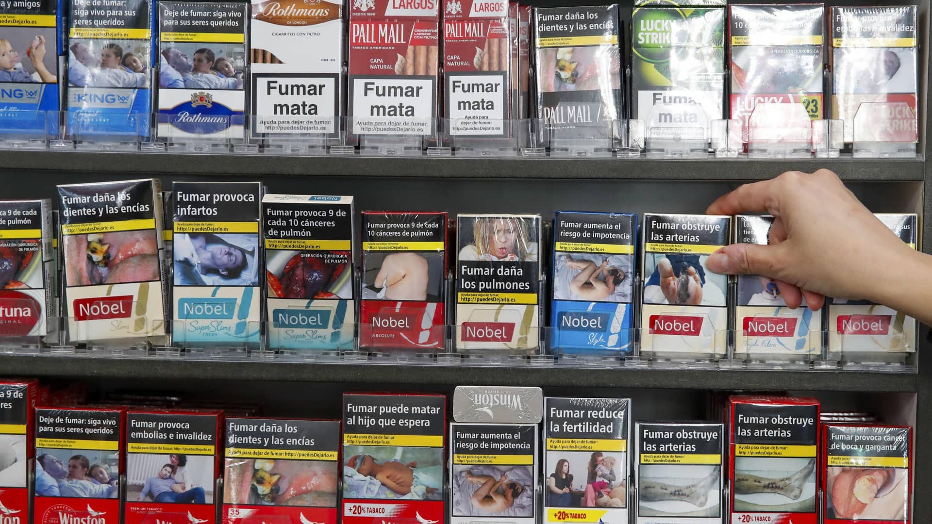 Cambia precio tabaco Una mano cogiendo cajas de tabaco