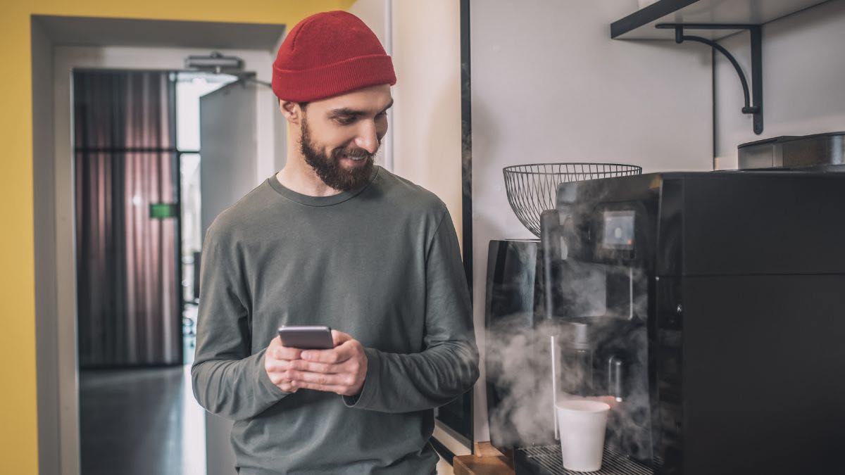 Joven sirviéndose café oficina