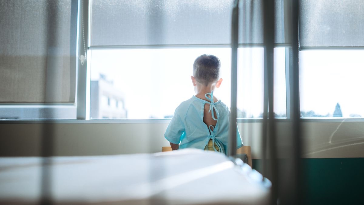 Niño mirando por la ventana de un hospital