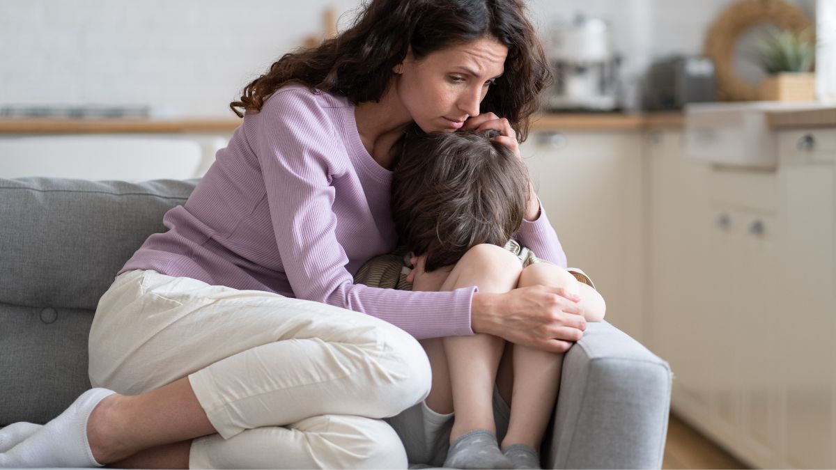 Una madre abraza a un niño triste.